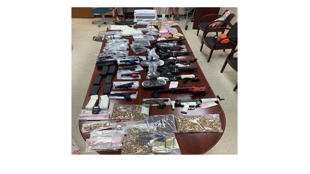 Photograph of drugs and guns laid out on a table.