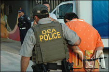 DEA agent brings defendant for processing.