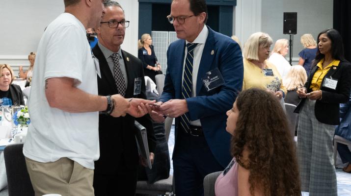 Jon DeLena and Principal Deputy Administrator Louis J. Milione shaking hands with a family member at the Family Summit