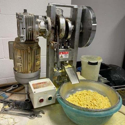 Pill press and bowl of yellow pills 