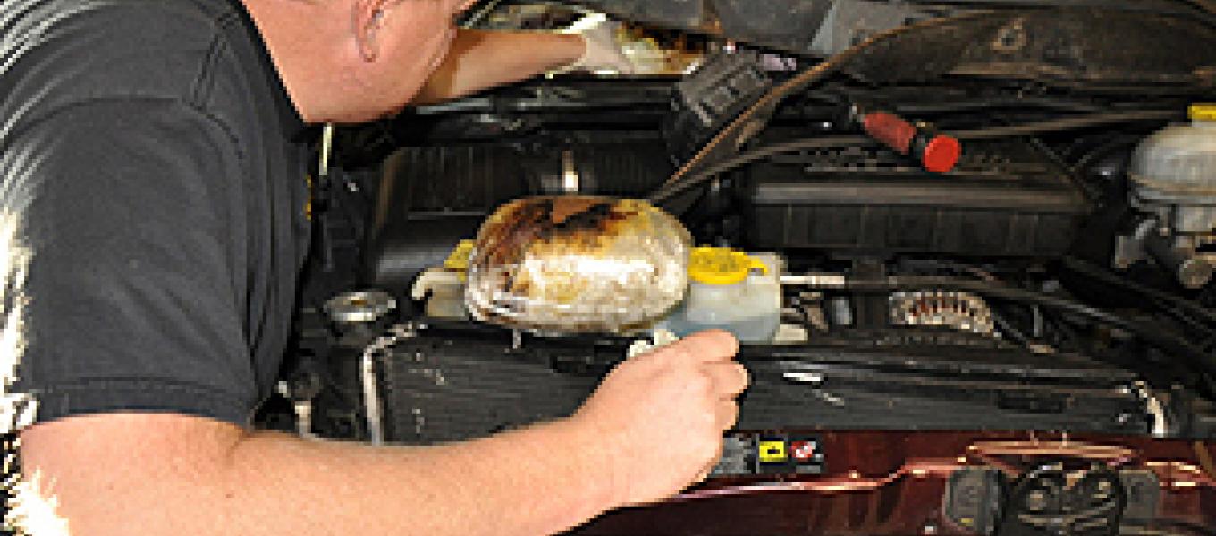 DEA Agent removing 10 pounds of meth concealed in the engine compartment of vehicle.